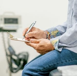 man sitting in doctors office filling out questionnaire