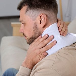 Man holding a heating pad on his neck