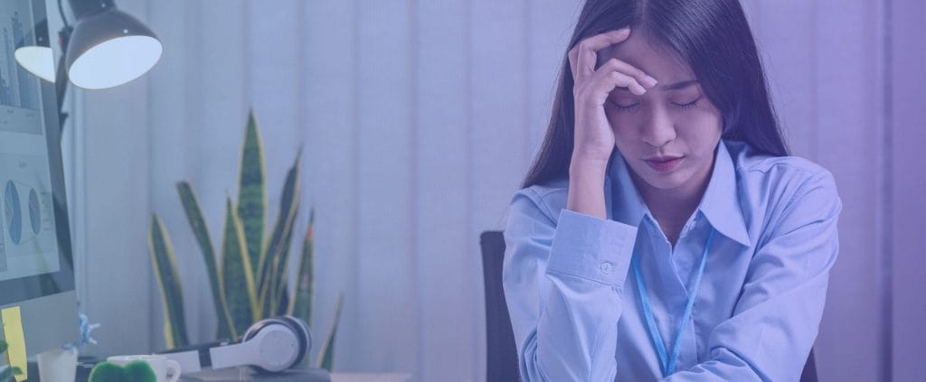 Woman sitting at desk in office with migraine