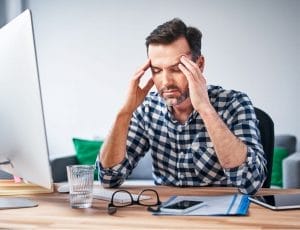 Man sitting at desk in office with migraine