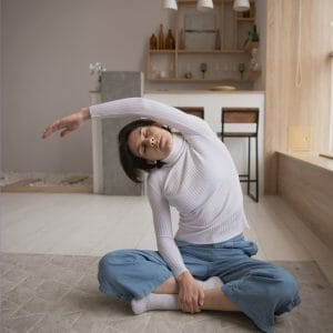 Woman sitting on floor gently stretching