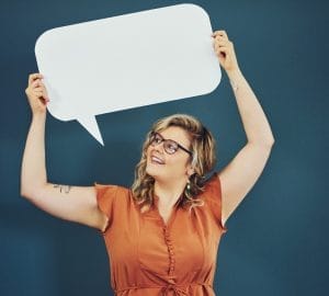 Blonde woman wearing glasses holding up a white speech bubble